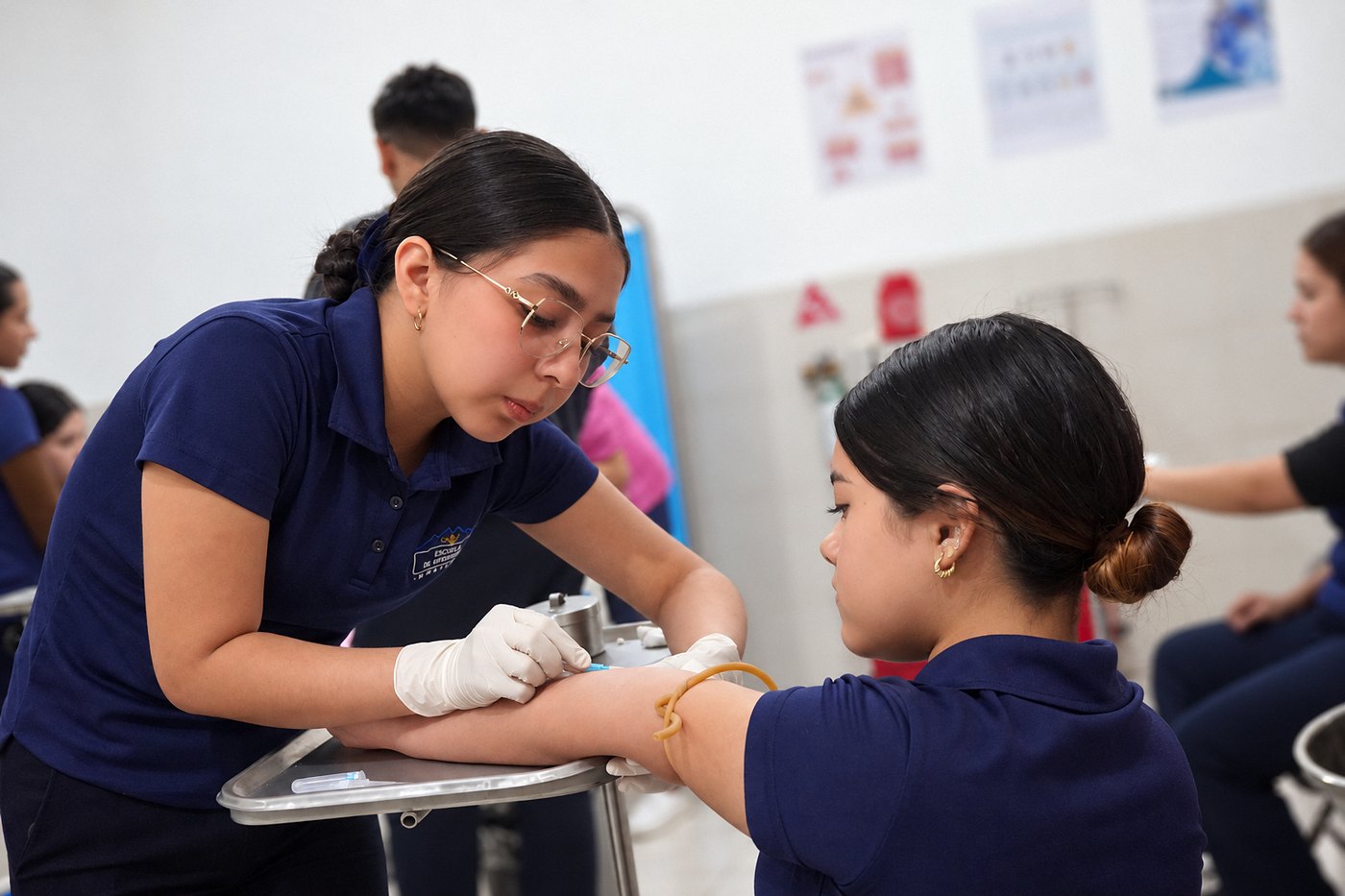 Alumna de Enfermería canaliza el brazo de una compañera durante la práctica